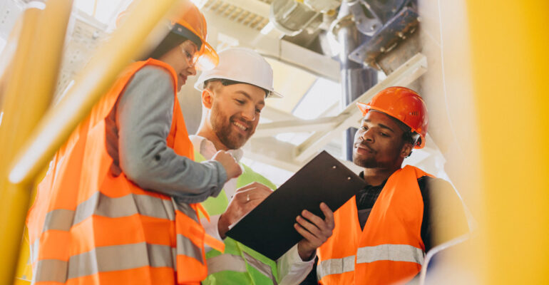 Three people discussing a plan at a factory